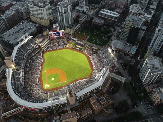 Aerial view of Petco Park lit up at dusk in downtown San Diego