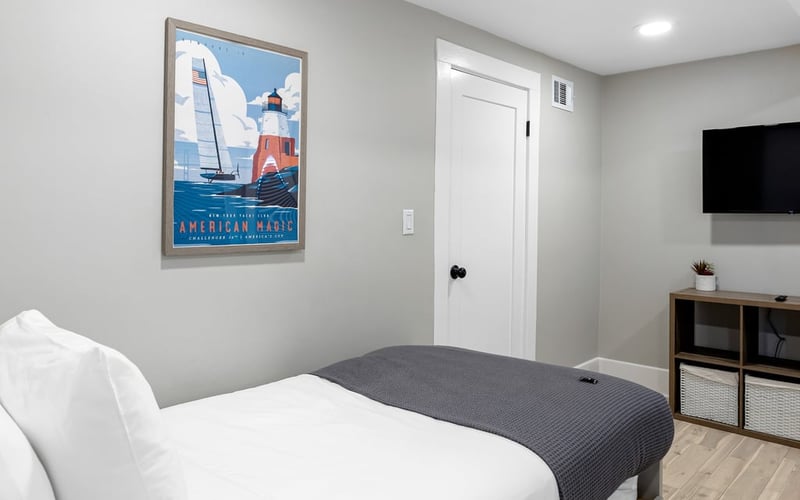Twin bedroom seen from the doorway, with the bed, wall-mounted TV, shelving and sailing artwork