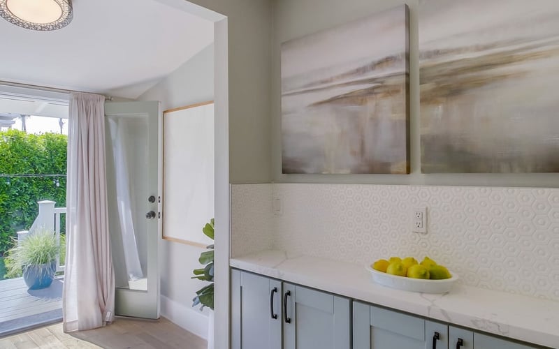 Kitchen counter with a bowl of lemons beside French doors opening to the sunlit side patio